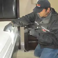 Bed bug inspection technician checking a mattress and bed frame for signs of infestation in Lincoln, NE