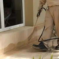 General pest control technician spraying exterior perimeter around a home in Lincoln, NE
