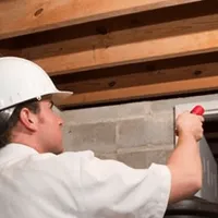 Termite inspection technician checking a basement wall and framing for termite activity in Lincoln, NE