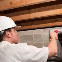 Termite inspection technician checking a basement wall and framing for termite activity in Lincoln, NE